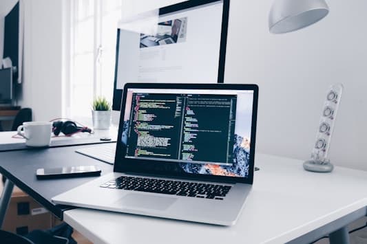 Laptop on a desk showing a code editor